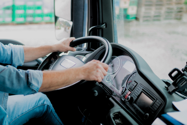 A close up of hands on a steering wheel.