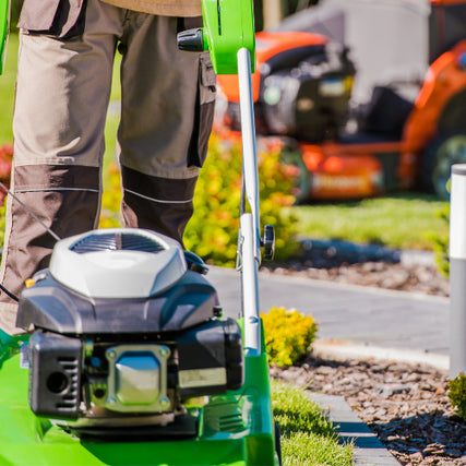 LandscapingA close up of a landscaper standing behind a pushmower.