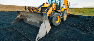 A loader smoothing out blacktop with it's bucket.