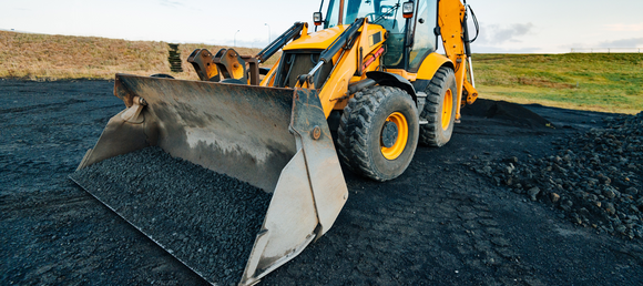 A loader smoothing out blacktop with it's bucket.